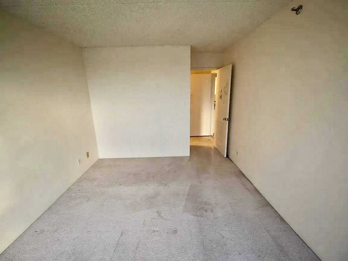 A room with a white wall and a doorway leading to another room.